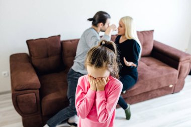 Mutsuz küçük kız yüzünü kapatıyor. Gürültülü aile tartışmasından muzdarip.,