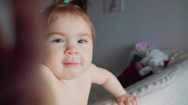 Kameraya bakan tatlı bir kız bebek. Çalıyor ve gülümsüyor.,