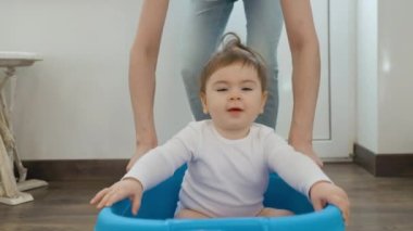 Heyecanlı genç anne koşuyor plastik kutuları küçük şirin bebekle itiyor.