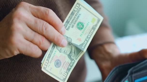 Vista da vicino delle mani di un vecchio uomo che gli aggiunge banconote da un dollaro al portafoglio. — Video Stock