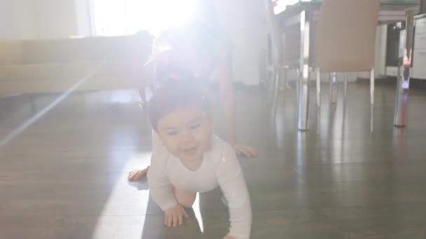 Gateando divertido bebé chica en bodysuit ella está dirigiéndose a su madre — Vídeos de Stock