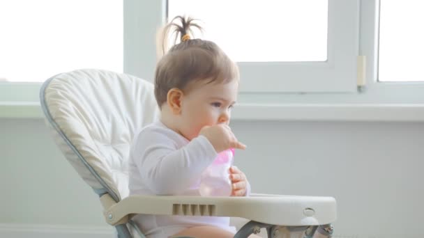 Mignon bébé fille jouer avec cuillère en plastique, près de la fenêtre de la maison. — Video