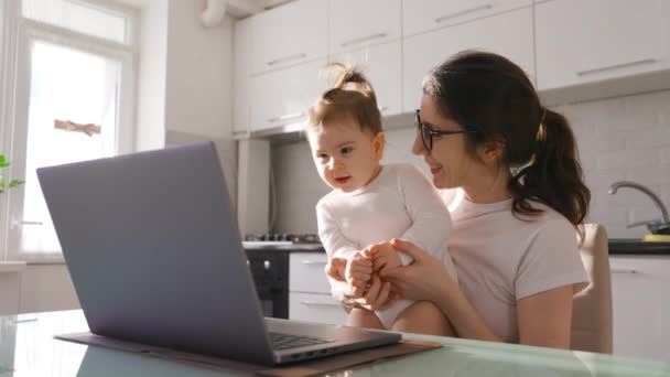 Jong opgewonden vrouw moeder met bril en baby dochter video bellen op laptop — Stockvideo