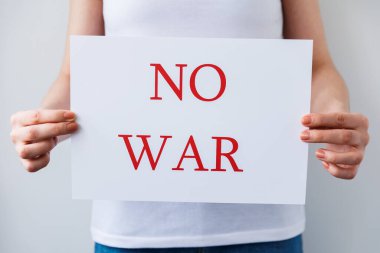 Bir protestocunun elleri karton pankartı tutarken savaş yok. Rus işgalini protesto ediyorlar..