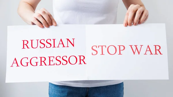 Закрыть руки протестующего, держащего картонное знамя со словами "русский агрессор остановит войну" — стоковое фото