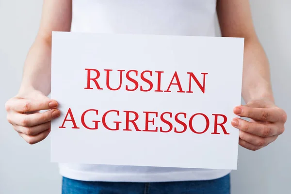 Закрыть руки протестующего, держащего картонное знамя со словами "русский агрессор" — стоковое фото