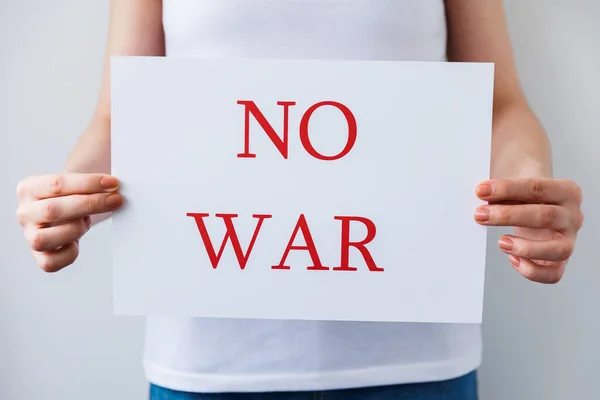 Großaufnahme eines Demonstranten, der ein Pappbanner mit der Aufschrift "No War" in den Händen hält. Protest gegen die russische Invasion. — Stockfoto