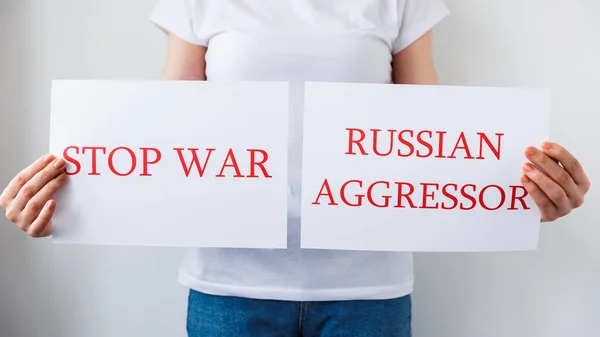 Закрыть руки протестующего, держащего картонное знамя со словами "русский агрессор остановит войну". — стоковое фото