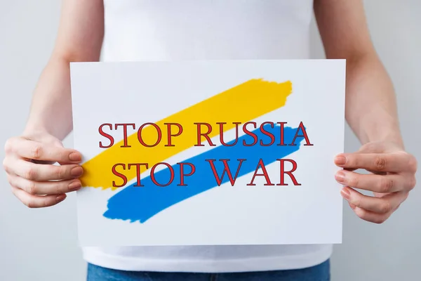 Крупным планом женщина держит в руках плакат с изображением украинского флага, в котором говорится, остановить войну остановить Россию. — стоковое фото