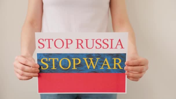 Mains de femme tient une affiche avec l'image du drapeau russe, qui dit arrêter la guerre arrêter la Russie. — Video