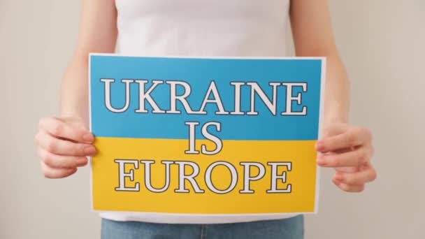 Žena ruce drží plakát s obrázkem ukrajinské vlajky, který říká, že ukrajinské je Evropa — Stock video