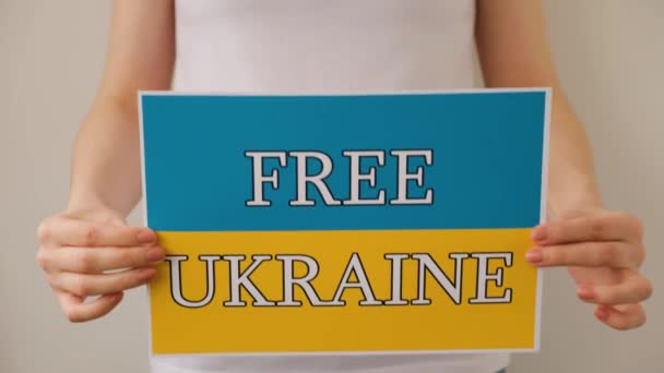 Руки женщины держат плакат с изображением украинского флага, на котором написано:. — стоковое видео