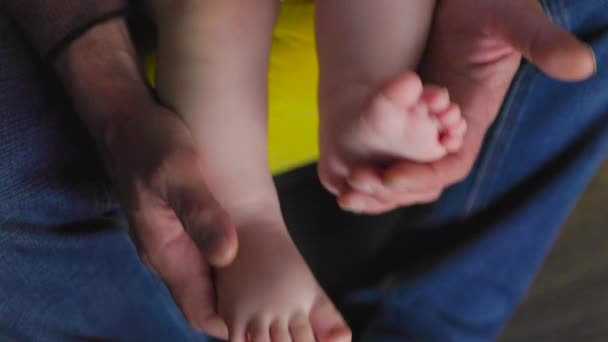 Закрывай, дедушка держит за руки детские ножки, играет с новорожденным — стоковое видео