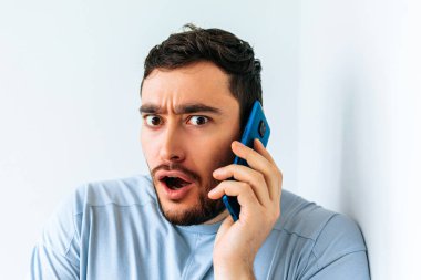 Genç sakallı adam telefonda konuşuyor. Korkunun şok edici ifadesi.