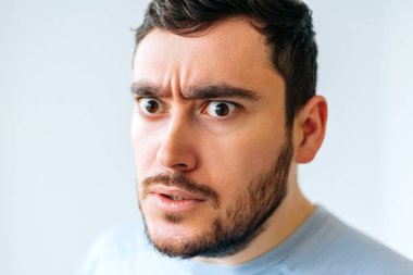 Şok olmuş, sinirli, sakallı, genç bir adamın portresi.