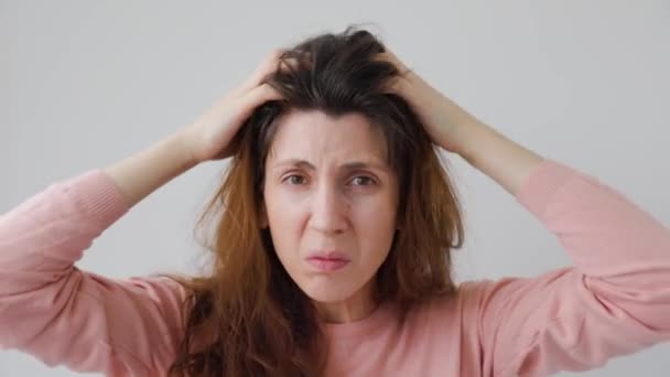 Mujer joven infeliz se rasca la cabeza con las manos causadas por la caspa — Vídeos de Stock