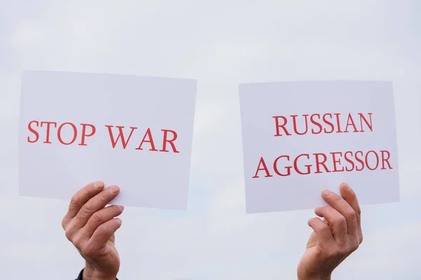 Закрыть руки протестующего, держащего картонное знамя со словами "русский агрессор", — стоковое фото