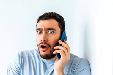 Genç sakallı adam telefonda konuşuyor. Korkunun şok edici ifadesi.