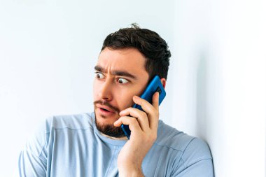 Genç sakallı adam telefonda konuşuyor. Korkunun şok edici ifadesi.