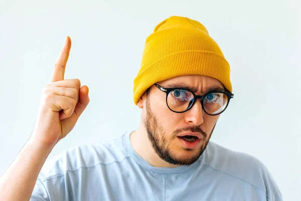 Vit stilig man med glasögon och gul hatt pekande uppåt — Stockfoto