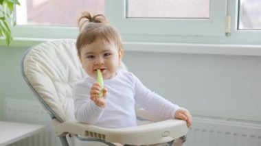 Evin penceresinin yanında plastik kaşıkla oynayan tatlı bir kız..