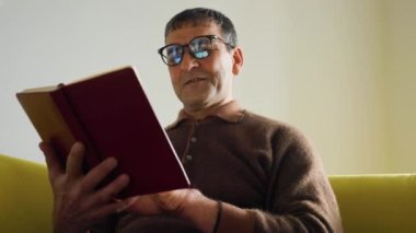 Yaşlı Asyalı profesör tarihçi evde eski kitapları okuyor.