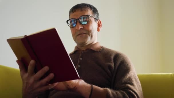 Старик азиатский профессор историк читает старую книгу дома — стоковое видео