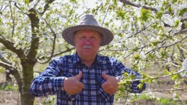 Şapkalı yaşlı, mutlu çiftçi başparmak işareti gösteriyor.