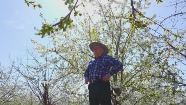 Старый фермер в шляпе кладет руки на ремень. — стоковое видео