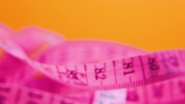 Close-up de uma fita métrica rosa e amarela em colorido — Vídeo de Stock