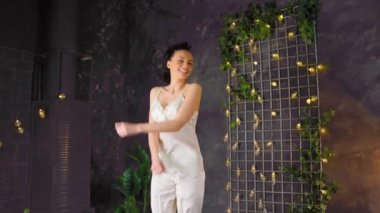 Pijamalı mutlu, zayıf kadın esmer yatakta zıplıyor.