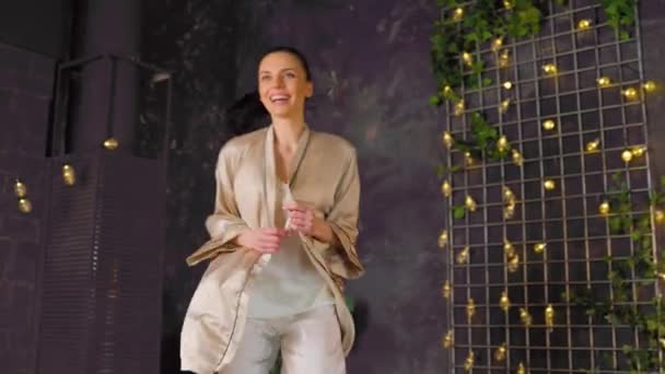 Caucasian joyful fresh brunette woman in pajamas jumping on bed — Stockvideo