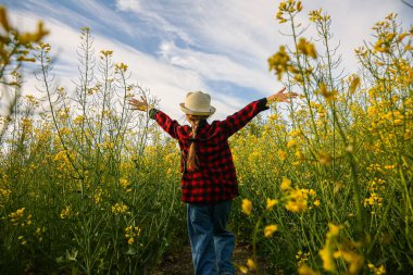Kollarını açmış koşan mutlu bir çocuğun arka görüntüsü.