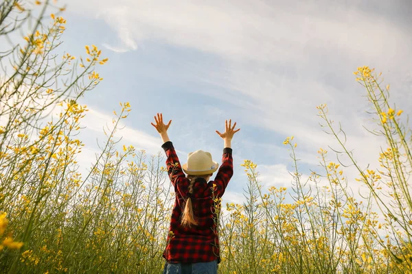 Rear view of a kid little girl jump into the field and raise their hands — Stock Photo, Image