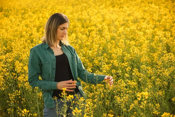 Ung kvinna bonde undersöker raps gröda — Stockfoto