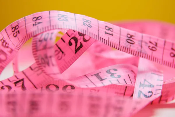 close up of a pink measure tape on white rotating background, rotation, macro measuring tape