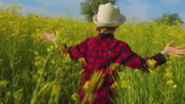 Kolları kola tohumu tarlasında koşan mutlu çocukların arka görüntüsü. Mutlu özgür kız çocuğu park arazisinde koşuyor.