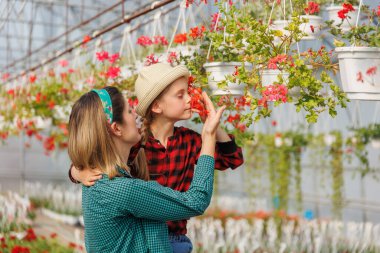 Güzel bir anne ve kız çocuğu serada çiçekleri analiz ederken izliyor. Bitki teftişi ve kontrol, kadın ve çocuk. Gelecek nesil için deneyim paylaşımı