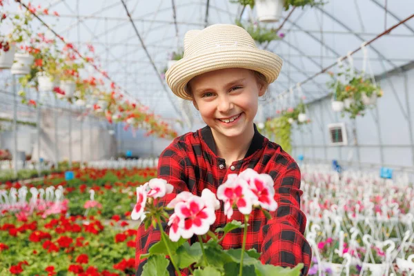 Serada çiçeklerle gülümseyen beyaz, genç bir kız çocuğu. Kameraya bakan mutlu çocuk, serada çalışmak dışında. Boşluğu kopyala