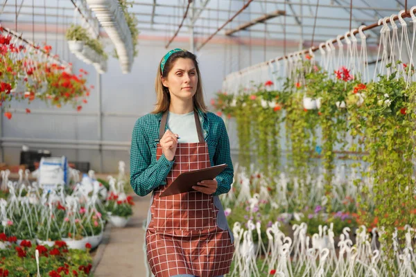 american Scientist woman with holding book of flower during research experiment in flower garden. Female gardener in a greenhouse analyzing some flowers, copy space