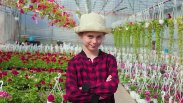 正面の眺め 腕を交差させた女の子がカメラを覗き込む 温室内にあり 各植物を別々に探索しています — ストック動画