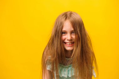 front view portrait of smiling preteen children girl with messed hair, isolated on yellow background. Beautiful happy child looking at camera and with disheveled hair on head. Hair care. clipart