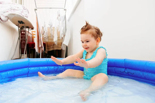 beautiful and cute happy baby girl having fun in the small pool at home. little children happy cheerful one summer day in the small indoor pool