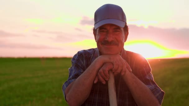 キャップを離れて見て喜んでラテンアメリカの農家と戻り 陽気にカメラに直面し 日没で笑顔を返します 成功したシニア農家の肖像とともに カメラで微笑む — ストック動画