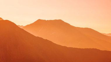 Silhouetted orange mountains and horizon at Fagaras mountains, Moldoveanu peak. mountains at sunset, national park. Scenic View Of Mountains Against Cloudy Sky During Sunset