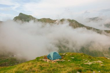 Tent on the background of the misty mountains. hiking tent in the mountains in summer. Camping above the hills in the the with the aerial view.