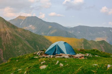 Tent on the background of the mountains. hiking tent in the mountains in summer. Camping above the hills in the the with the aerial view.