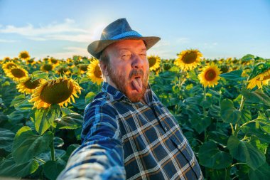 senior farmer make grimace is excited and happy taking selfie. sticks his tongue out. male farmer is crazy and fun