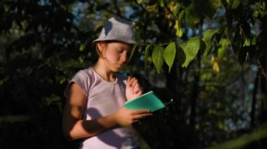 pretty children girl Naturalist Scientist Explores Plant Life and Insect Life take notes in his notebook. Smart Curious kid Botanist and Entomologist Explores Nature.