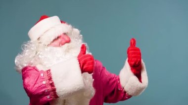 Mavi arka plan manzaralı yeni yıl Noel Baba 'sı iki eli kırmızı eldivenli baş parmağını gösteriyor. De Frost her zaman tatildir, stüdyoda çekim yapar, mutlu Peder Frost. Boşluğu kopyala.